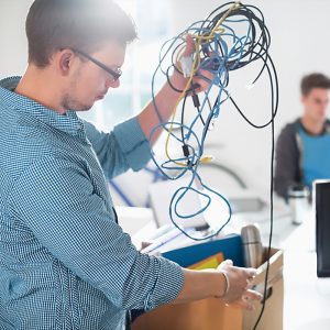 Businessman untangling cords in office